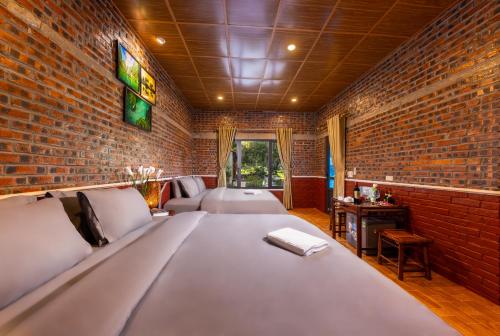 een kamer met een bed en een bakstenen muur bij Trang An Spring Garden Homestay in Ninh Binh