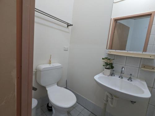 a white bathroom with a toilet and a sink at Studio 21 - Wright Lodge in Adelaide