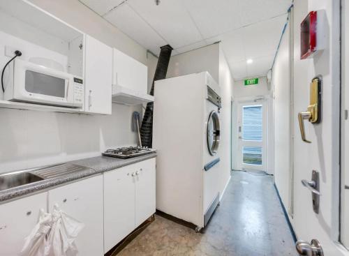 a white kitchen with a microwave and a refrigerator at Studio 21 - Wright Lodge in Adelaide