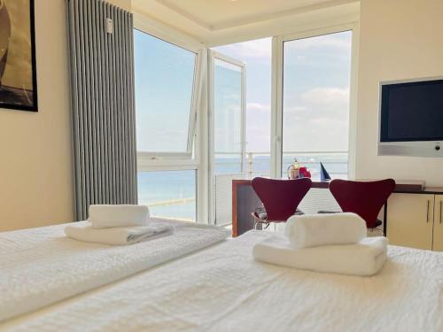 a bedroom with a bed with two chairs and a large window at Penthaus Horizont mit Meerblick in Lübeck