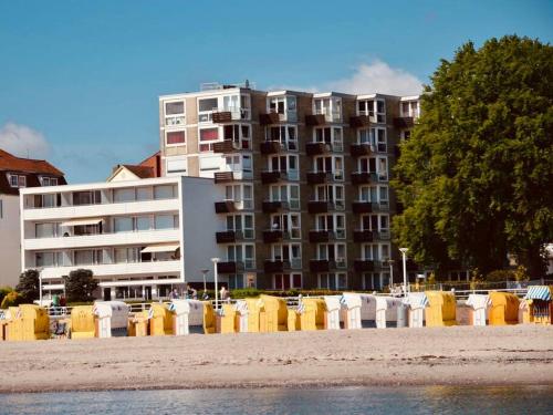 a large apartment building next to a beach with chairs at Penthaus Horizont mit Meerblick in Lübeck