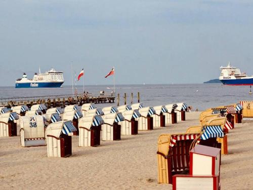 a row of beach chairs on a beach with two ships at Penthaus Horizont mit Meerblick in Lübeck