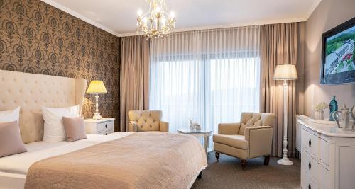 a bedroom with a bed and a chair and a television at Victor's Seehotel Weingärtner Bostalsee in Bosen-Eckelhausen