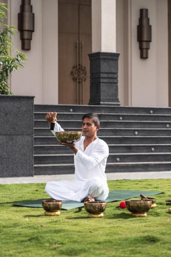 a man sitting on the grass holding a plate of food at Dusit Thani Himalayan Resort Dhulikhel, Nepal in Dhulikhel
