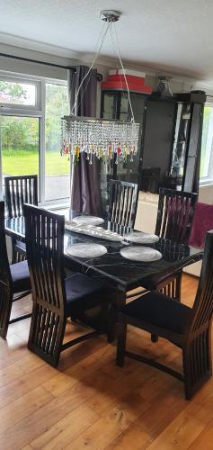 a black dining room table with chairs and a chandelier at Rosemount in Sligo