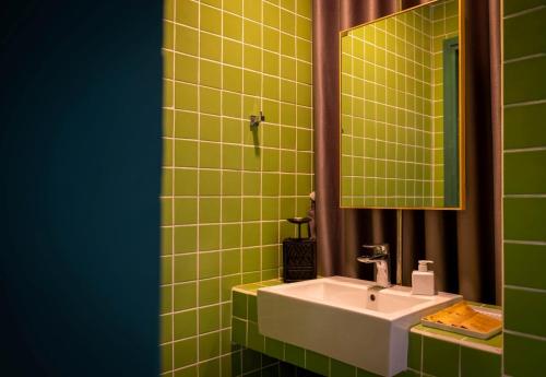 a green tiled bathroom with a sink and a mirror at The Note Dalat in Da Lat