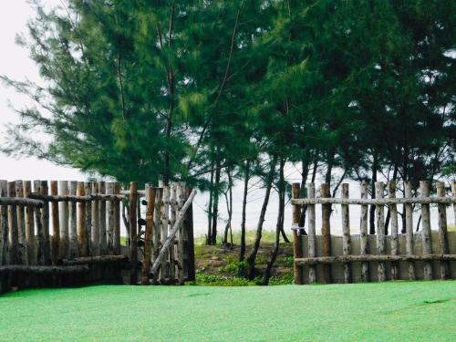 a wooden fence with a tree in the middle of a field at Lagi Retreat homestay Home ngay mặt biển Lagi in La Gi