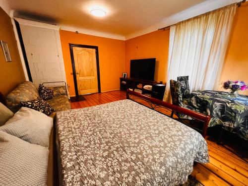um quarto com paredes cor-de-laranja, uma cama e uma televisão. em Unique Mailo cottage em Riga
