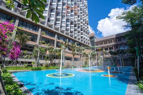 a large pool with water fountains in front of a building at M Continental by Mandala Mui Ne in Phan Thiet