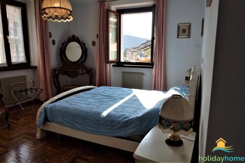 een slaapkamer met een bed met een blauw dekbed en een raam bij Lake Garda Home in Riva del Garda