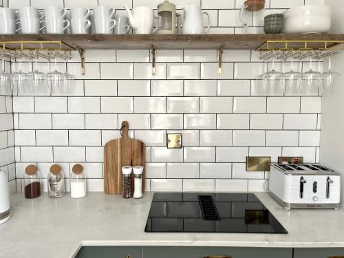 a kitchen with white tiled walls and a counter top at The Old Tearoom At Ty Llywelyn By Birch Stays in Conwy