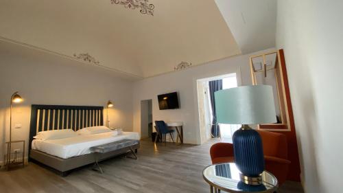 a bedroom with a bed and a table with a lamp at Lanterne Magiche Ortigia Suites in Syracuse