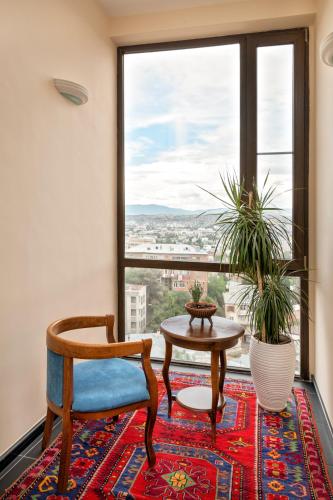 a room with a chair and a table and a large window at GINGER Hotel in Tbilisi City