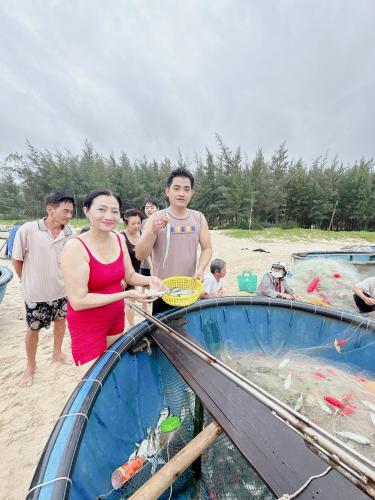 a woman is standing next to a boat on the beach at Lagi Retreat homestay Home ngay mặt biển Lagi in La Gi