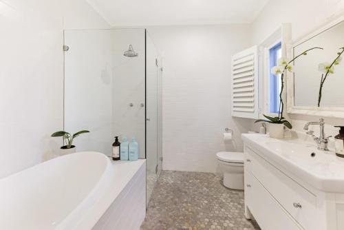 uma casa de banho branca com uma banheira e um WC em Hatton Ville Fireplace Village 5 Minutes Gardens em Leura