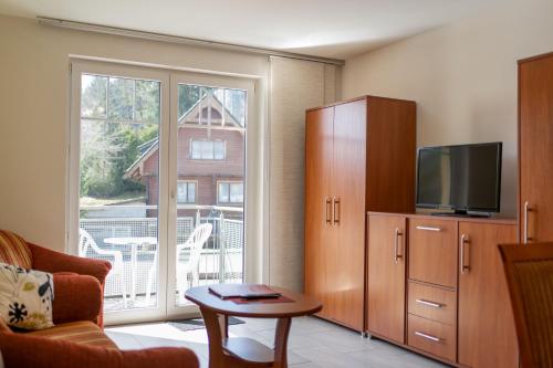 a living room with a tv and a large window at Gaststätte & Pension Waldschlösschen in Oberhof