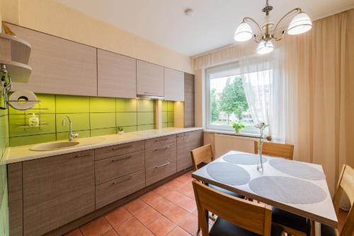 a kitchen with a table and a sink and a window at A.P. Apartment in Šiauliai