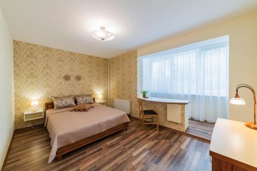 a bedroom with a bed and a desk and a window at A.P. Apartment in Šiauliai