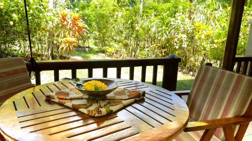 a wooden table with a bowl of flowers on it at Cocotier du Rocher in La Digue