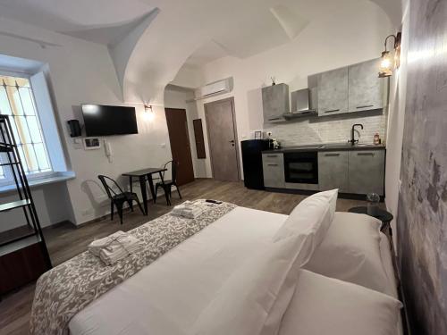 a bedroom with a white bed and a kitchen at Chagall Charme in Asti
