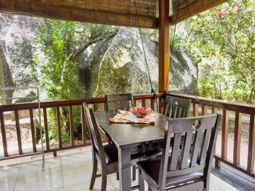 - une table et des chaises sur une terrasse couverte dans l'établissement Cocotier du Rocher, à La Digue