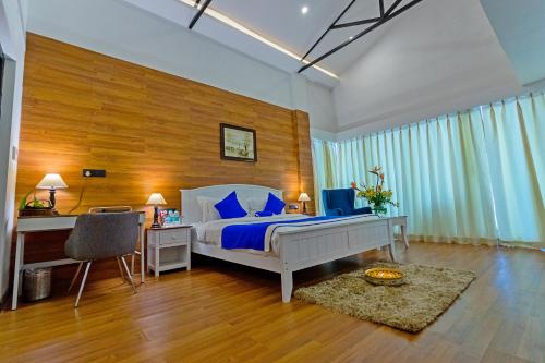 - une chambre avec un lit doté d'oreillers bleus et d'un bureau dans l'établissement Polo Orchid Resort Cherrapunjee, à Cherrapunji