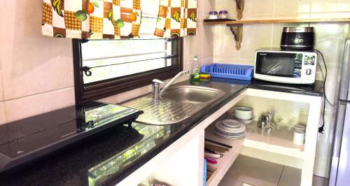 a kitchen with a sink and a microwave at Cocotier du Rocher in La Digue
