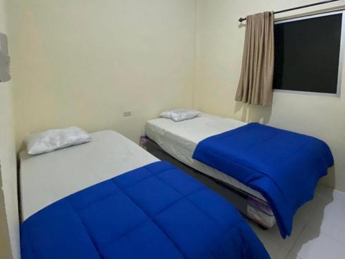 a bedroom with two beds with blue sheets and a window at Pondok Indah Syariah near Suzuya Mall Langsa RedPartner in Birimpontong