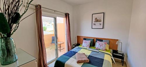 um quarto com uma cama com almofadas coloridas e uma janela em Ferienhaus SUN & OCEAN in Gran Tarajal em Gran Tarajal