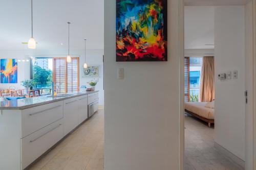 a kitchen with white cabinets and a painting on the wall at Park view Avalon Apartment District 1 HCM City in Ho Chi Minh City