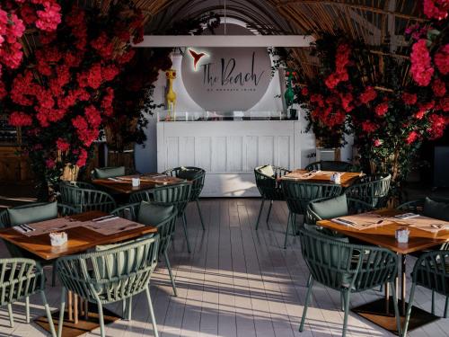 a restaurant with tables and chairs and red flowers at The Unexpected Ibiza Hotel - Ushuaïa Club entrance included in Playa d'en Bossa
