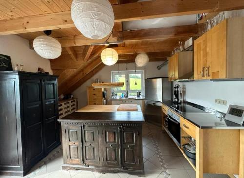a large kitchen with wooden ceilings and a black island at Panorama-Suite Birkenbeul in Birkenbeul