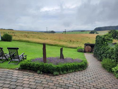 um jardim com um banco e flores num campo em Panorama-Suite Birkenbeul em Birkenbeul