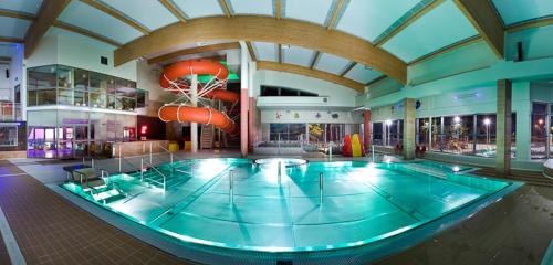 a large swimming pool in a large building with a gym at Hotel Sportowy in Ostrzeszów