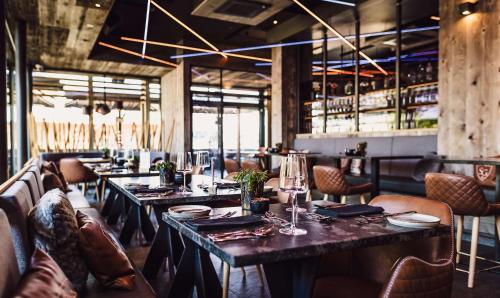 um restaurante com mesas e cadeiras e um bar em Stockinggut by AvenidA Hotel & Residences em Leogang