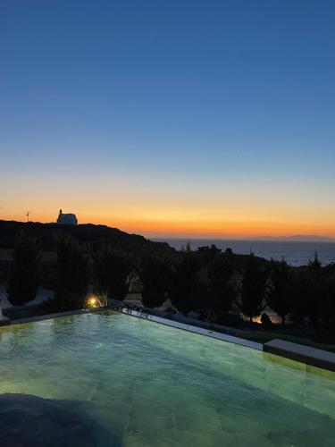 a large swimming pool with a sunset in the background at Saint John Oia-Villa With Private Heated Pool in Oia