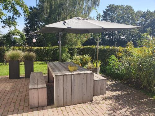 a picnic table with an umbrella and two benches at Recreatiewoning De NieuwenHof in Melderslo