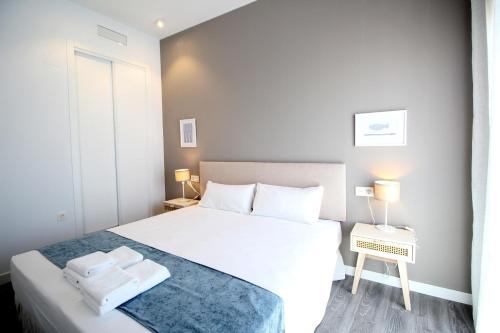 a bedroom with a white bed with two towels on it at Del Parque Flats Urban Relax in Málaga