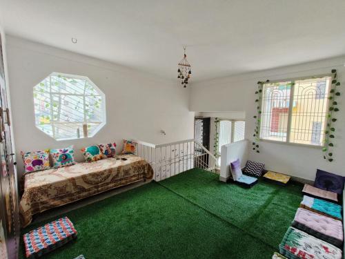a room with a bed and a window and green carpet at Tusker Tribe in Mysore
