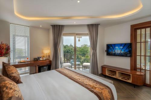 a bedroom with a bed and a tv and a balcony at Ngon Avatar Hotel in Pleiku