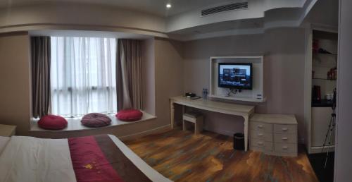 a bedroom with a desk and a tv on a window at Century Hotel Tongren in Tongren