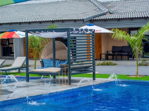uma piscina com um guarda-sol, uma cadeira e uma mesa em The Lux Hotel and Resorts em Louis Trichardt