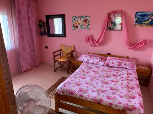 a pink bedroom with a bed and a fan at “Tek Riki” in Korçë