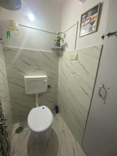 a bathroom with a white toilet and a shower at Couzy Cocoonn Stays in Nagpur