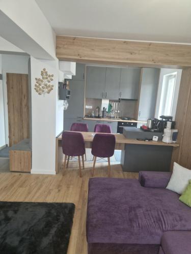 a living room with a purple couch and a kitchen at Casa Mov in Braşov