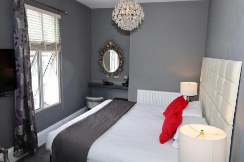 a bedroom with a large white bed with red pillows at Brighton Inn Boutique Guest Accommodation in Brighton & Hove