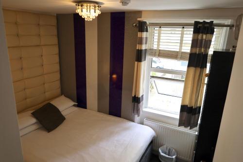 a small bedroom with a bed and a window at Brighton Inn Boutique Guest Accommodation in Brighton & Hove