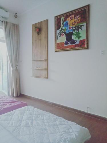 ein Schlafzimmer mit einem Bett und einem Bild an der Wand in der Unterkunft TRANG DOAN'S HOMESTAY in Ấp Tân Bình (2)
