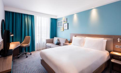 a hotel room with a large bed and a chair at Hampton By Hilton Belfast City Centre in Belfast
