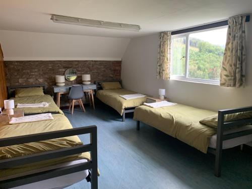 a room with three beds and a table and a window at Black Mountain Views in Velindre